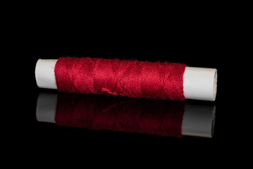 One whole sewing thread spool isolated on black glass