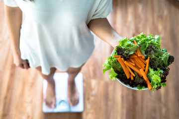 Women are weighing themselves with scales and holding healthy food, diet, lose weight, obesity top...