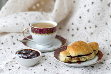 Cup of coffee and croissant with jam