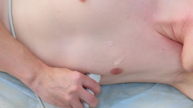 Doctor making echocardiography for man patient heart by using ultrasound equipment, closeup view. Cardiologist runs ultrasound sensor over man's chest. Diagnosis of internal organs.