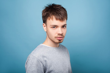 Portrait of concentrated confident brunette man with small beard and mustache in casual sweater looking attentively with intelligent serious expression. indoor studio shot isolated on blue background