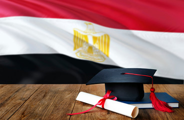 Egypt education concept. Graduation cap and diploma on wooden table, national flag background....