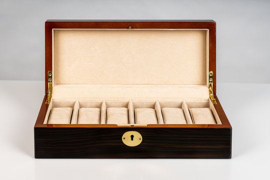 Empty brown wooden luxury jewelry watch case box with open lid and padded inside on white background.