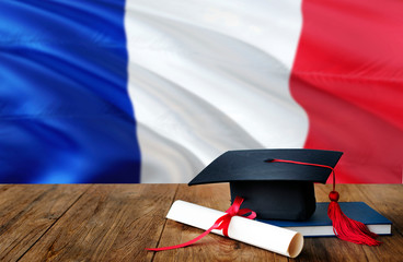 France education concept. Graduation cap and diploma on wooden table, national flag background....