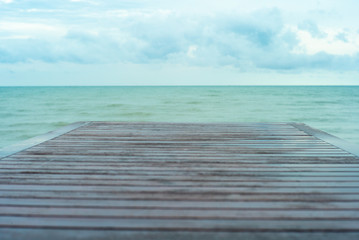 Fototapeta premium Selective focus on wooden table surface with blurred horizintal line and blue cloudy sky in background