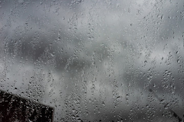 Rain drops on a window against cloudy sky. city in rainy season