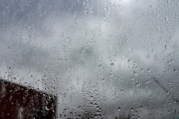 Rain drops on a window against cloudy sky. city in rainy season
