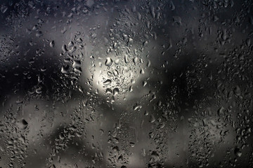 Rain drops on a window against cloudy sky. city in rainy season
