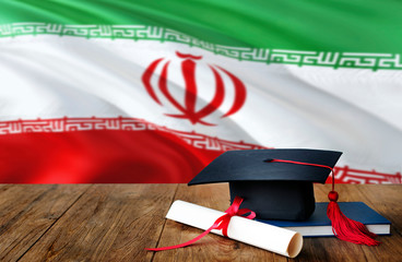 Iran education concept. Graduation cap and diploma on wooden table, national flag background. Succesful student.