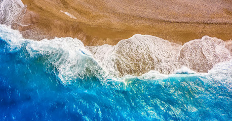 texture of sea surf with white waves, turquoise water and sandy shore