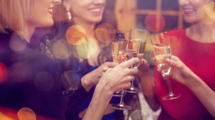 Women's hands with glasses of champagne. Ffriends celebrating Christmas or New Year eve party, while clinking glasses with sparkling wine