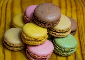 Colored macarons isolated on wooden dish, typical French dish