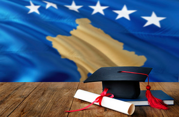 Kosovo education concept. Graduation cap and diploma on wooden table, national flag background. Succesful student.