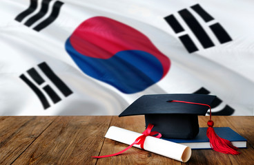 South Korea education concept. Graduation cap and diploma on wooden table, national flag...