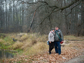 man and woman in a forest with red leaves in autumn outdoors