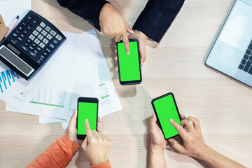 Business people hands using smart phone green screen on top view. Technology communication.