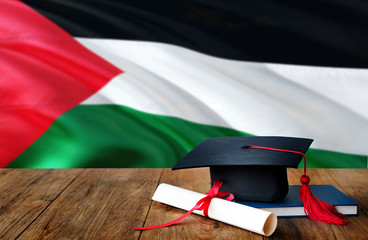 Palestine education concept. Graduation cap and diploma on wooden table, national flag background....