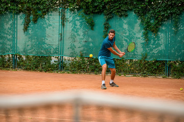 Skilled male tennis player at outdoor court - obrazy, fototapety, plakaty