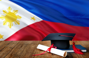 Philippines education concept. Graduation cap and diploma on wooden table, national flag...