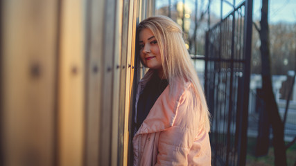 Fototapeta na wymiar A portrait of a beautiful girl, posing near a wooden fence at sunset in springtime.