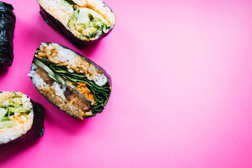 Vegan onigiri sandwich with tofu, spinach, carrot and cucumber on pink background. Japanese cuisine. Top view.