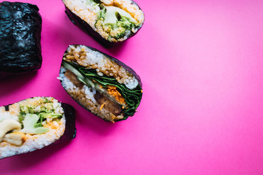 Vegan onigiri sandwith with tofu, carrot, cucumber and spinach on pink background. Japanese cuisine. Top view.
