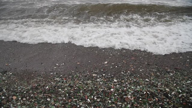 The famous beach with glass fragments stones in Russky Island, Vladivostok. Waves come to land. Environmental pollution
