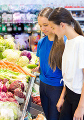 Teen girls shopping in supermarket reading product information. Choosing daily product.Concept of healthy food, bio, vegetarian, diet.