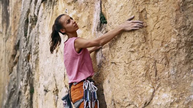 young female rock climber climbs on a cliff, searching, reaching and gripping hold. outdoors rock climbing and active lifestyle concept, slow motion stock footage