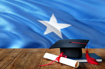Somalia education concept. Graduation cap and diploma on wooden table, national flag background. Succesful student.