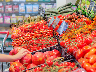 Female hand choosing tomatoes in the store. Concept of healthy food, bio, vegetarian, diet.