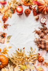 Vertical autumn background with yellow fall leaves, pumpkins, scarf,  cappuccino, burning candles, apples and rowan. Top view. Cozy autumnal layout with copy space. Seasonal arrangement. Top view