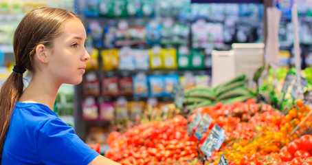 Teenage girl shopping in supermarket. Reading product information, Choosing daily product.