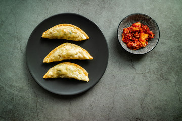Traditional Korean fried mandu with kimchi on concrete background. Top view.
