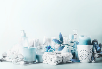 Beautiful blue white spa composition. Various cosmetic products with burning candles and flowers on...