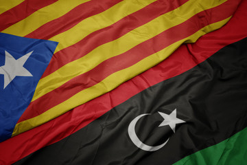 waving colorful flag of libya and national flag of catalonia.