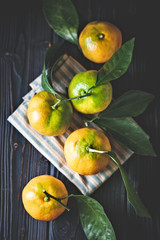 Tangerines with leaves on an old fashioned country table. Selective focus. Vertical.