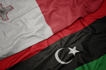 waving colorful flag of libya and national flag of malta.