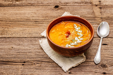 Autumn pumpkin cream soup. Traditional ingredients, healthy food concept. Napkin, vintage wooden background