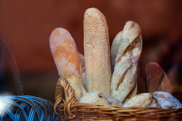 Wicker basket full of baguettes, tasty delicious crusty bread in bakery shopfront.