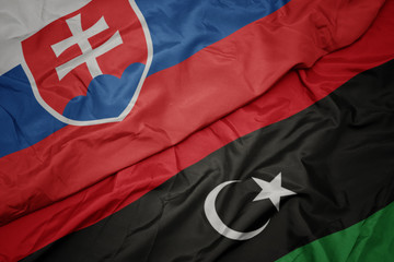 waving colorful flag of libya and national flag of slovakia.