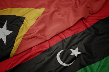 waving colorful flag of libya and national flag of east timor.