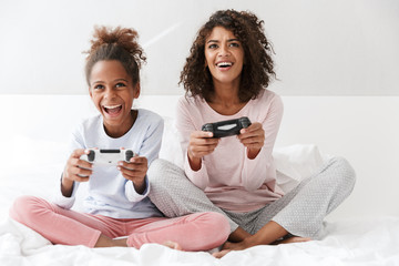 Image of american woman and little girl playing video games with joysticks