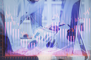 Double exposure of chart with businessman typing on computer in office on background. Concept of hard work.