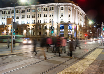 Passers-by cross the tram rails in the evening.