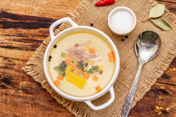 Transparent duck broth in bowl with vegetables. Traditional bouillon, healthy meal. Old wooden background