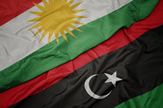waving colorful flag of libya and national flag of kurdistan.