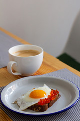 cup of coffee and toast with fried egg and red caviar