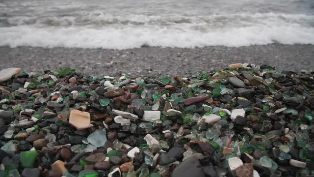 The famous beach with glass fragments stones in Russky Island, Vladivostok. Waves come to land. Environmental pollution