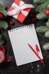 Fototapeta na wymiar Christmas or New year holiday background with blank Notepad open, fir branches and Christmas traditional decorations. Letter To Santa. Top view from copyspace